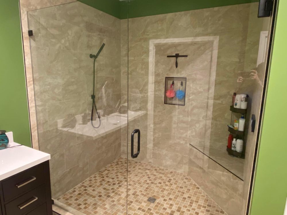 A bathroom with a walk in shower with a glass door.