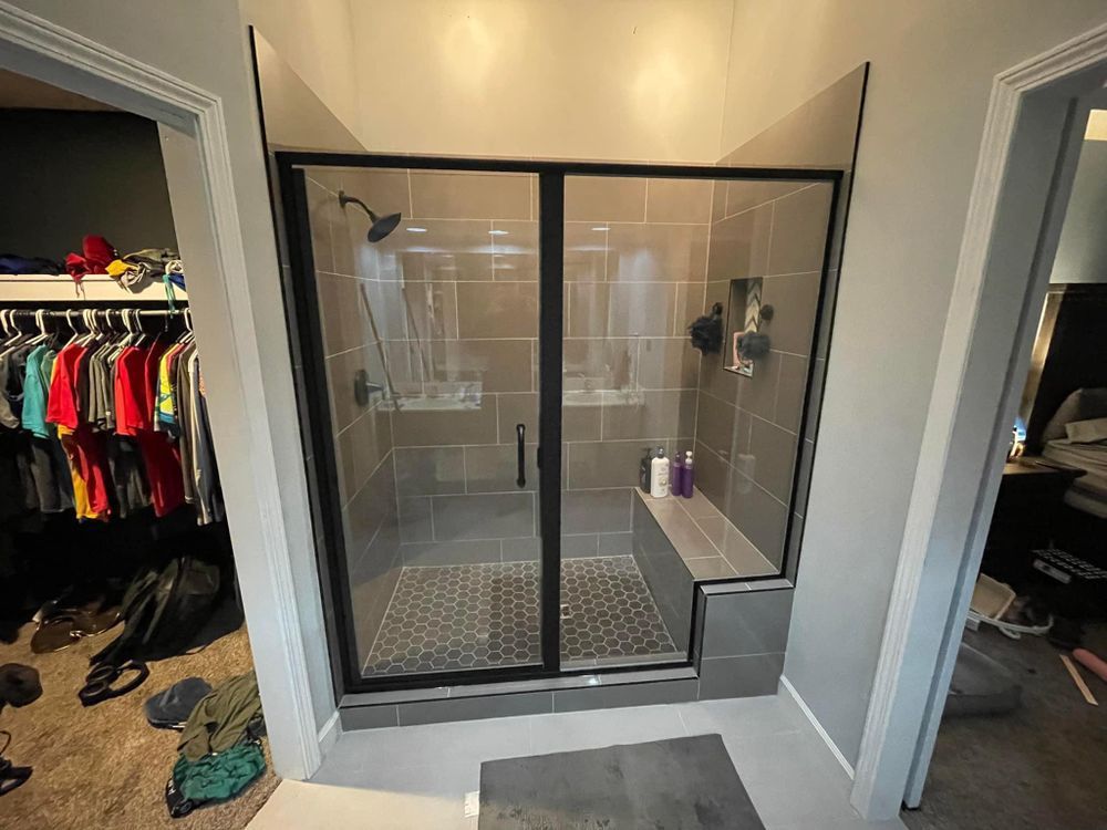A bathroom with a walk in shower and a closet.