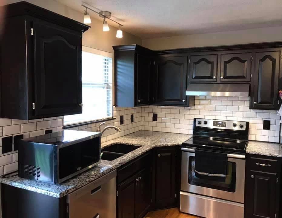 A kitchen with black cabinets and stainless steel appliances