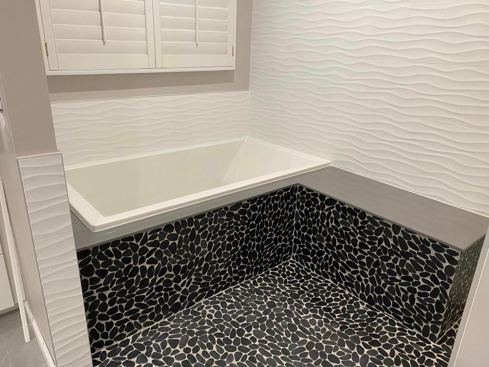 A bathroom with a bathtub and a black and white tile floor.