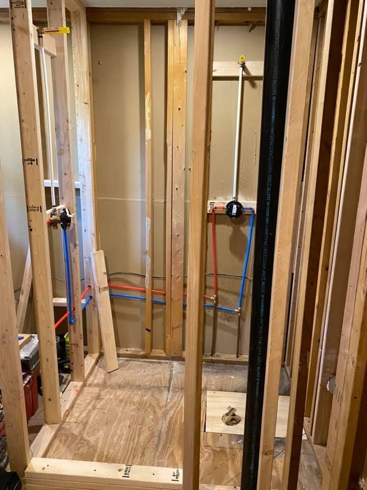A bathroom under construction with wooden beams and pipes.