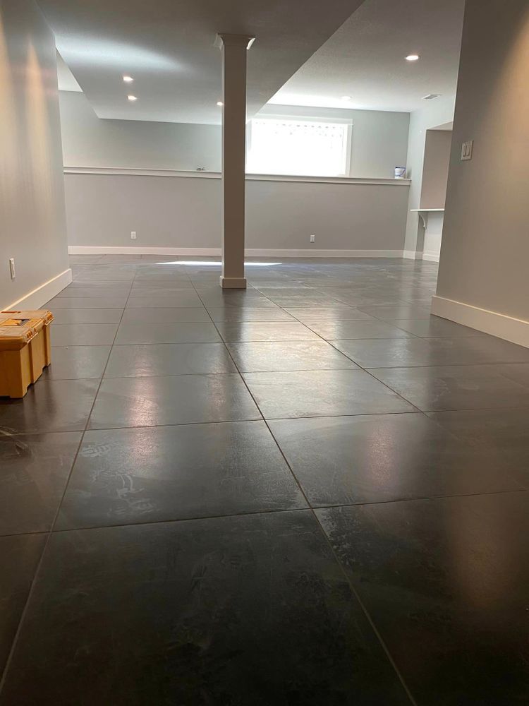 An empty basement with a black tile floor and white walls.