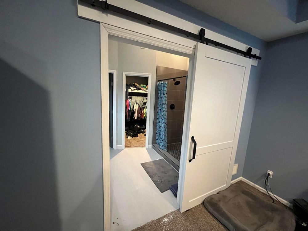 A bedroom with a sliding barn door leading to a bathroom.