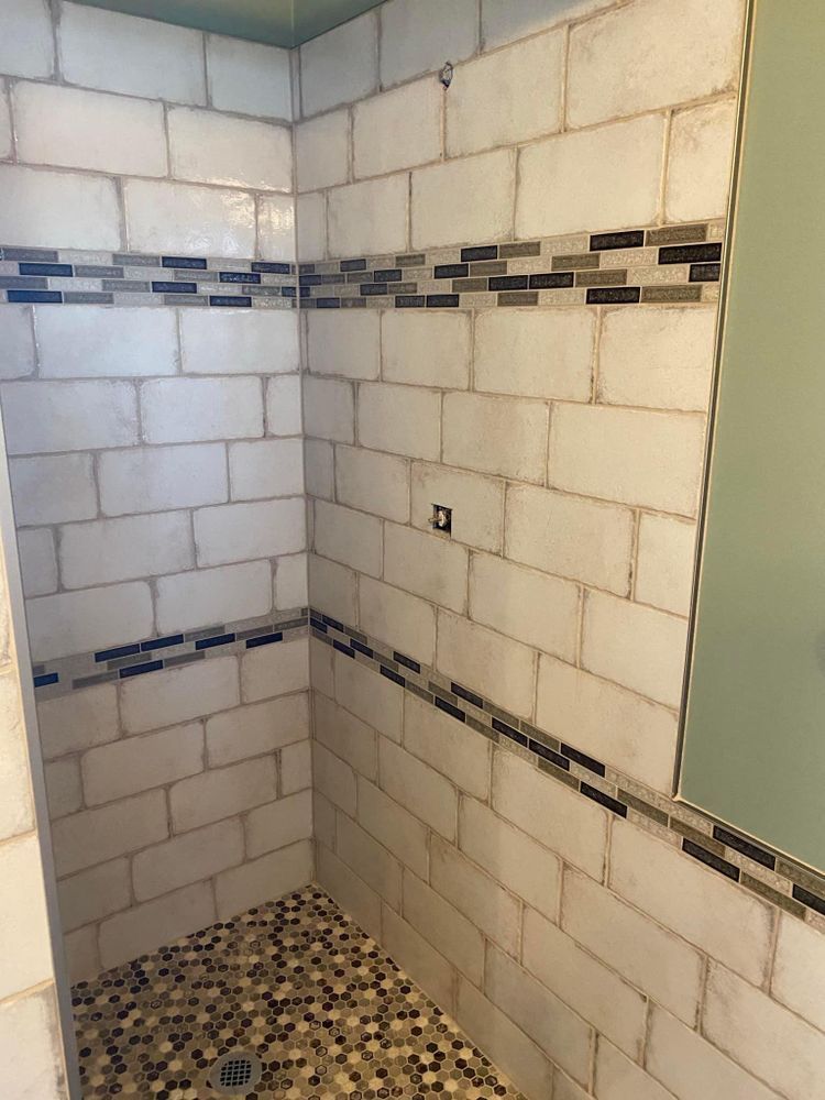 A shower with white tiles and a mosaic floor