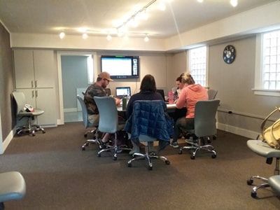 People seated around a table in a meeting room, working on laptops.
