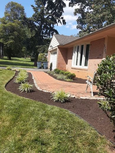 A house with a brick walkway leading to it and a bench in front of it.