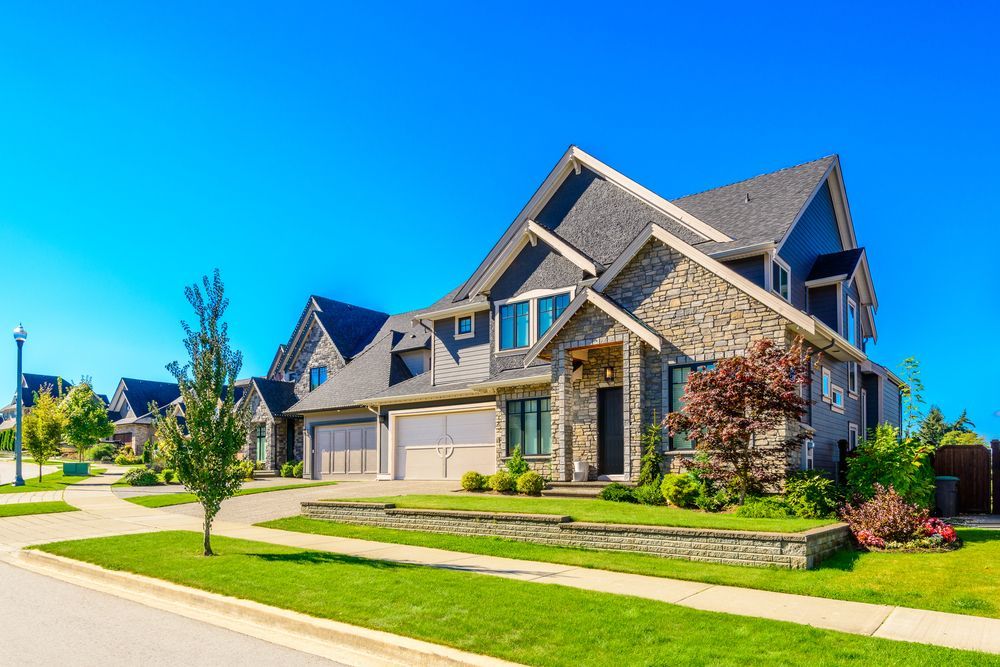 A large house is sitting on top of a lush green lawn in a residential neighborhood.