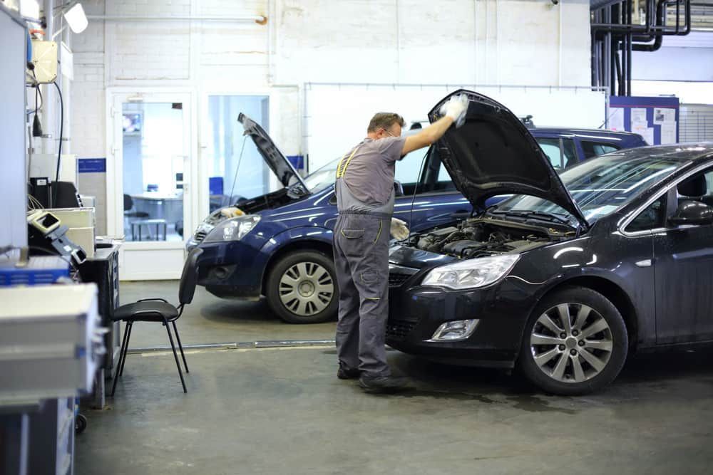 A Man Is Working On A Car In A Garage With The Hood Open — Wayne Devlin Mechanical In Bundaberg Central, QLD
