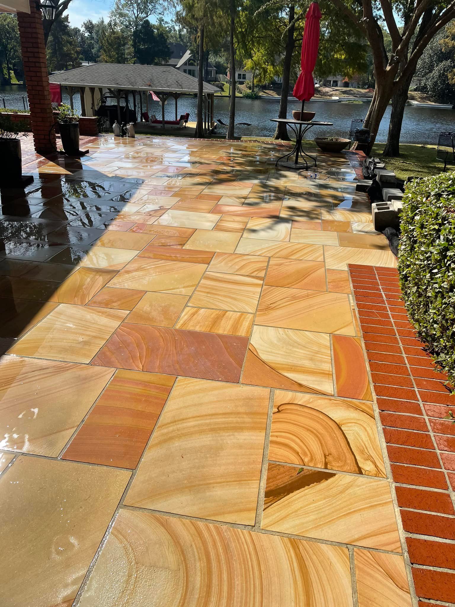 A tiled walkway leading to a lake with a red umbrella in the background.