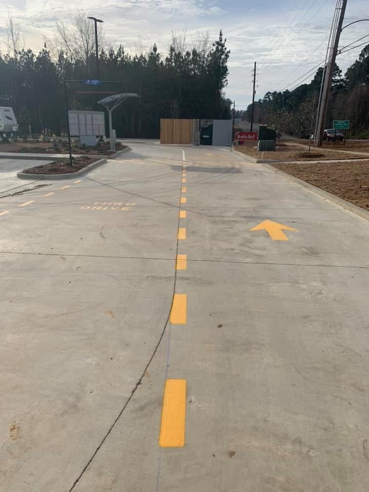 A concrete road with yellow lines and an arrow pointing to the right.