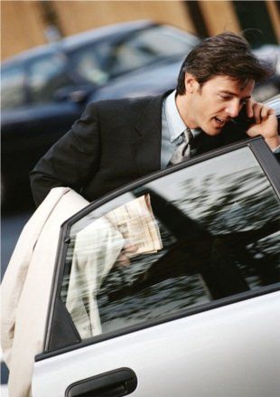 Man getting into a car whilst on the phone