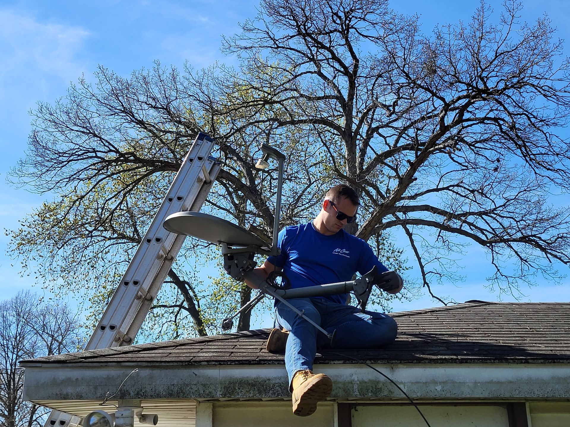 Man Seating In The Roof While Installing The Satellite And Antenna - All Clear Clean Out & Junk Removal Services - Chicago, IL