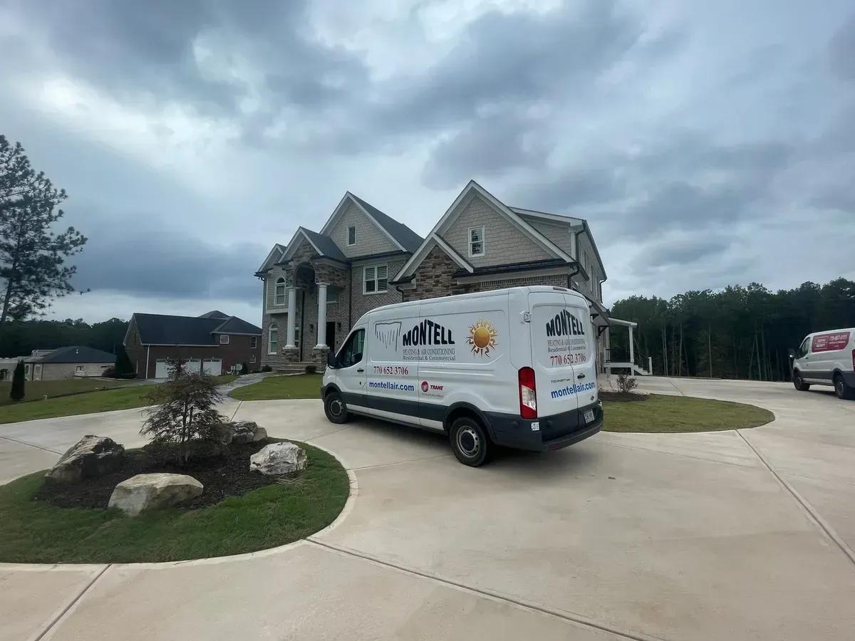 A white van is parked in front of a large house.
