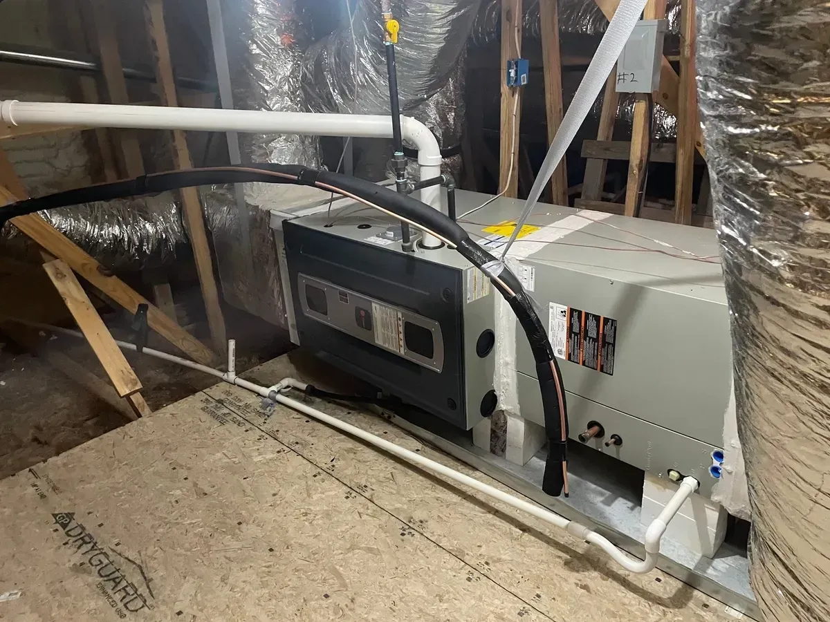 An air conditioner is sitting in the attic of a house.