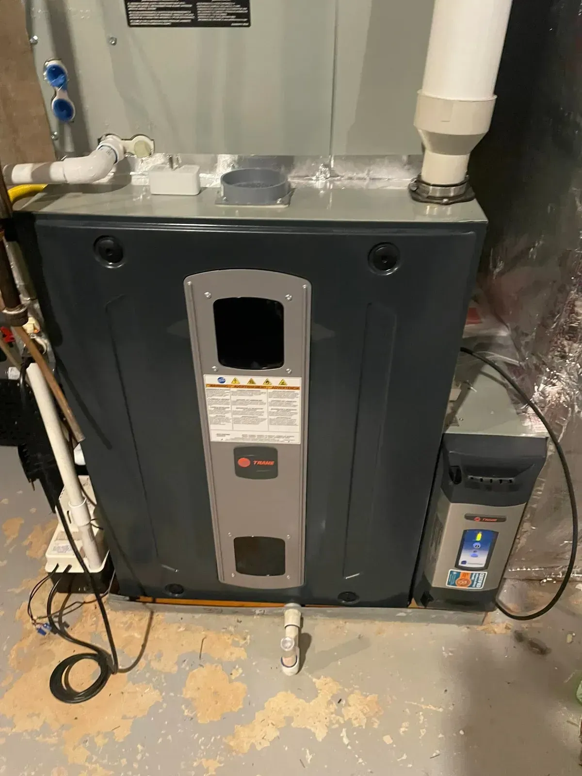 A large air conditioner is sitting in a basement next to a humidifier.