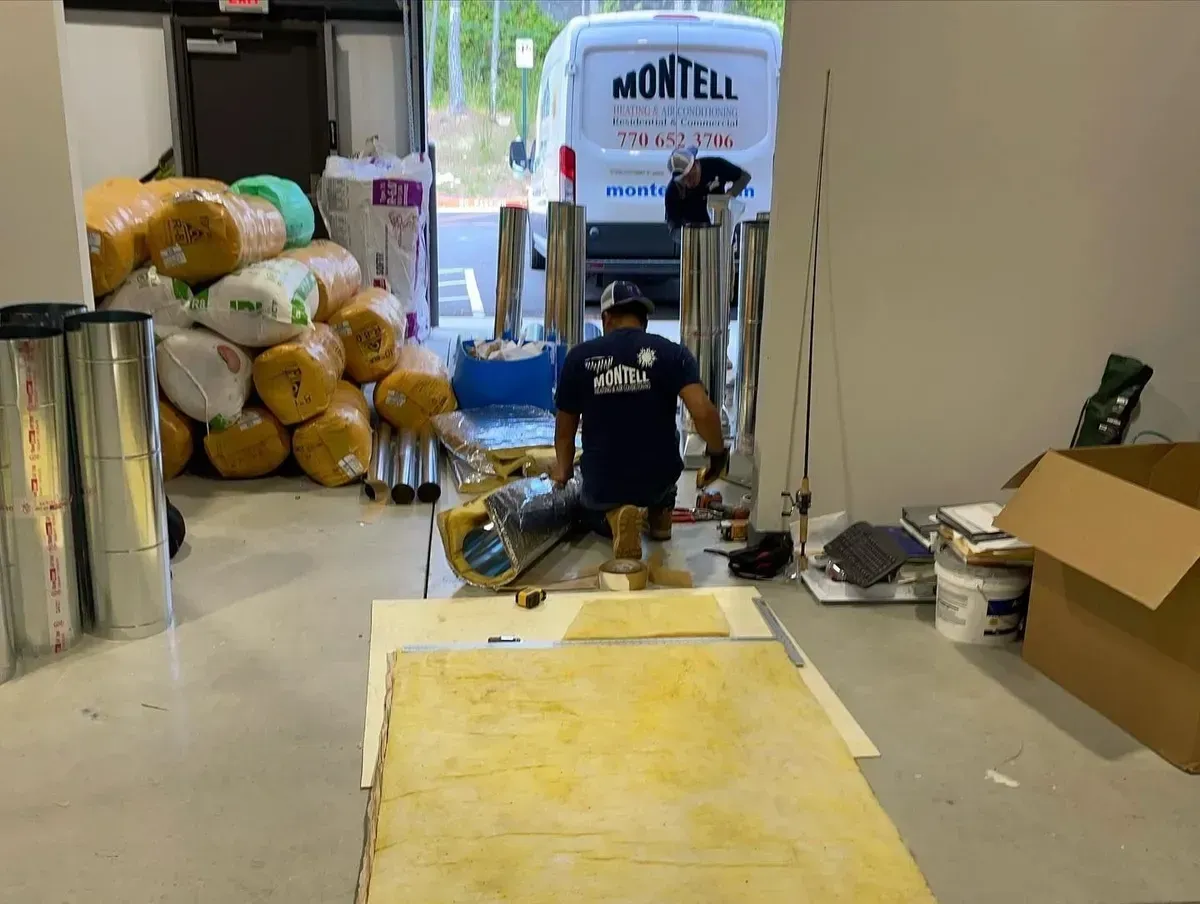 A man is kneeling on the floor in a room with a white van in the background.