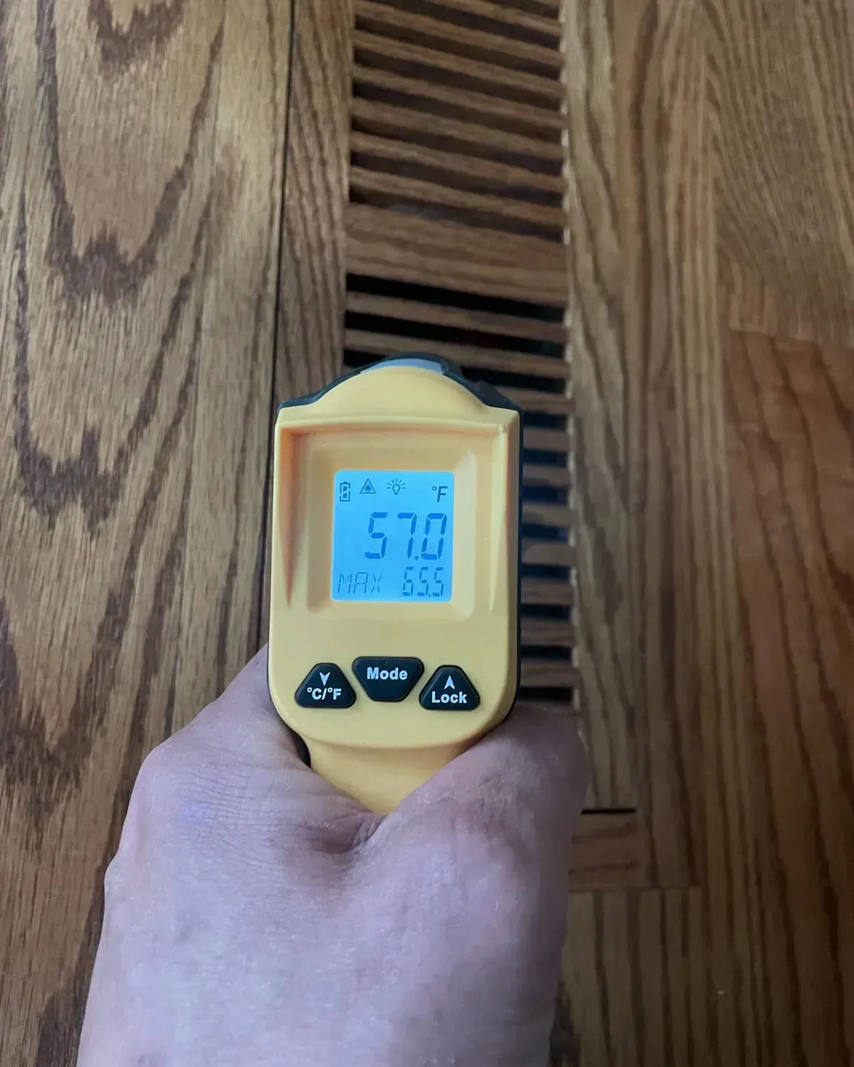 A hand is holding a yellow thermometer that reads 570 degrees