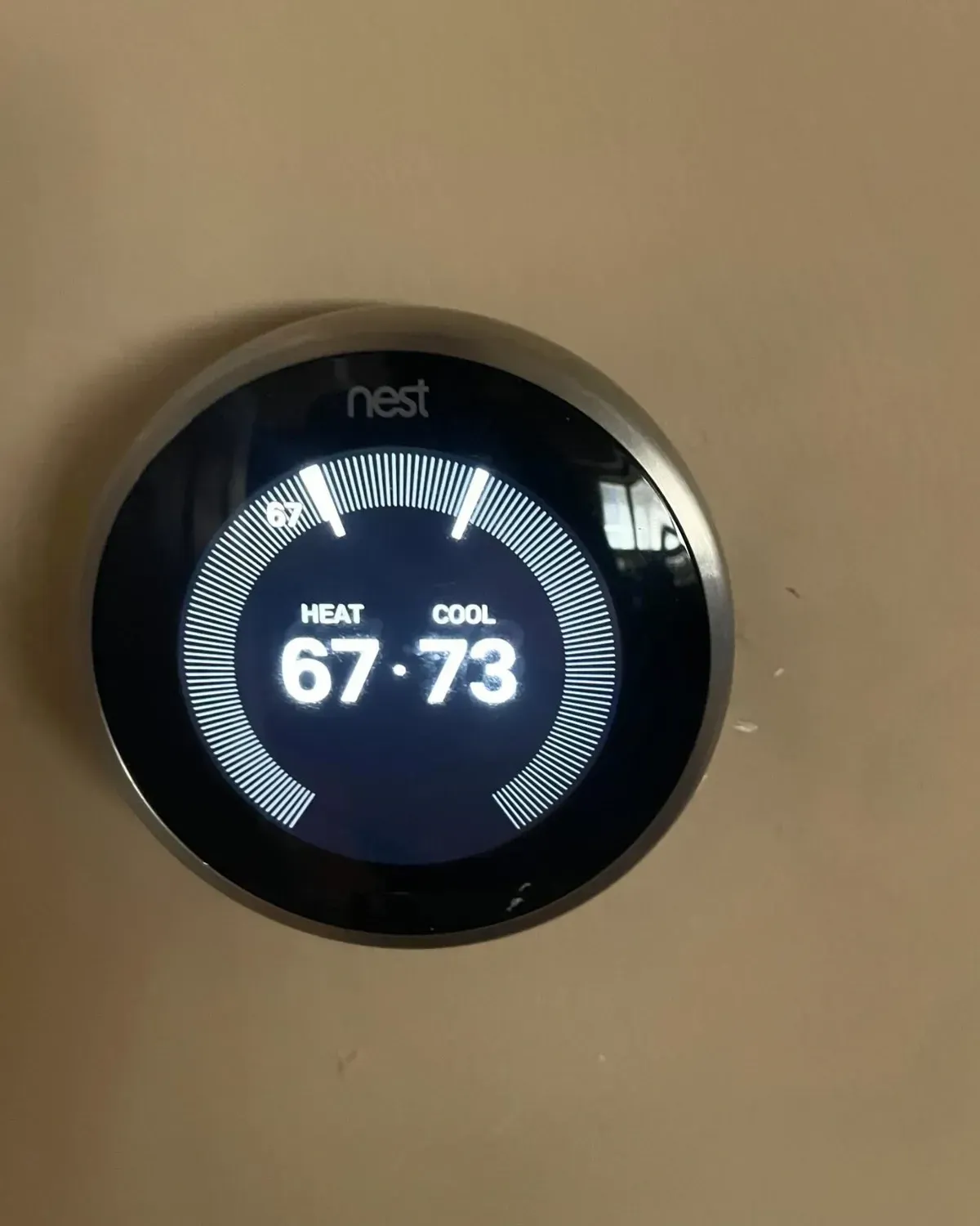 A nest thermostat is sitting on a white wall.