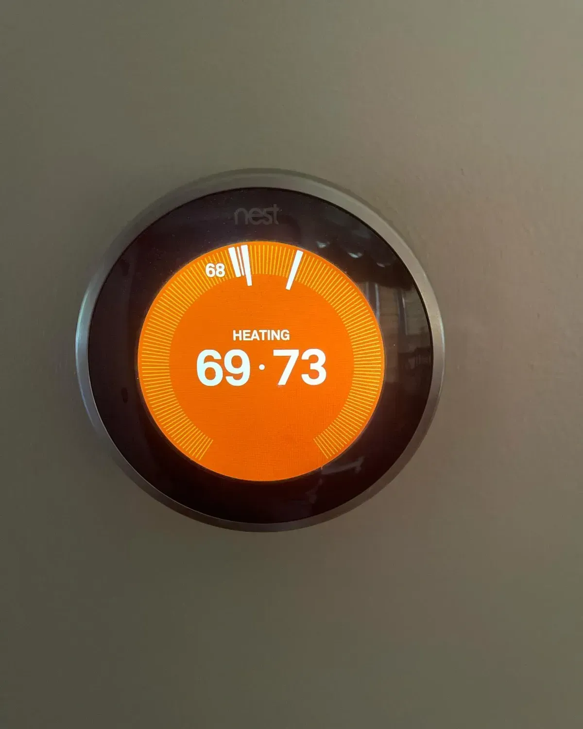 A nest thermostat is displaying the temperature at 69 degrees