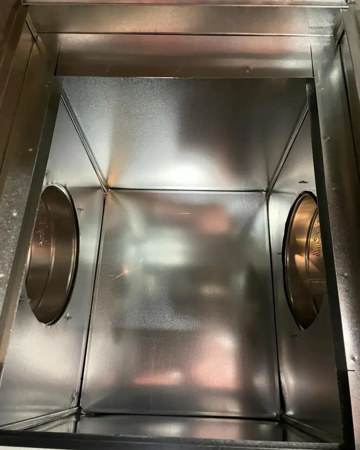 The inside of a metal box with two holes in it.