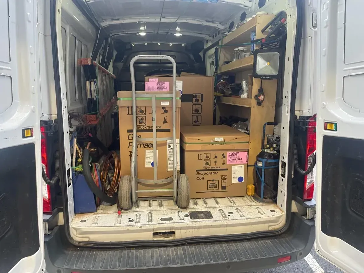 The back of a van is filled with boxes and tools.