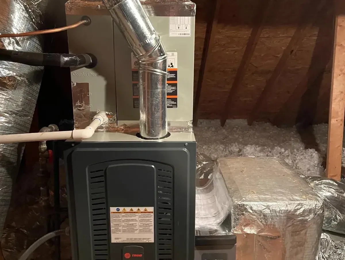 An air conditioner is sitting in the attic of a house.