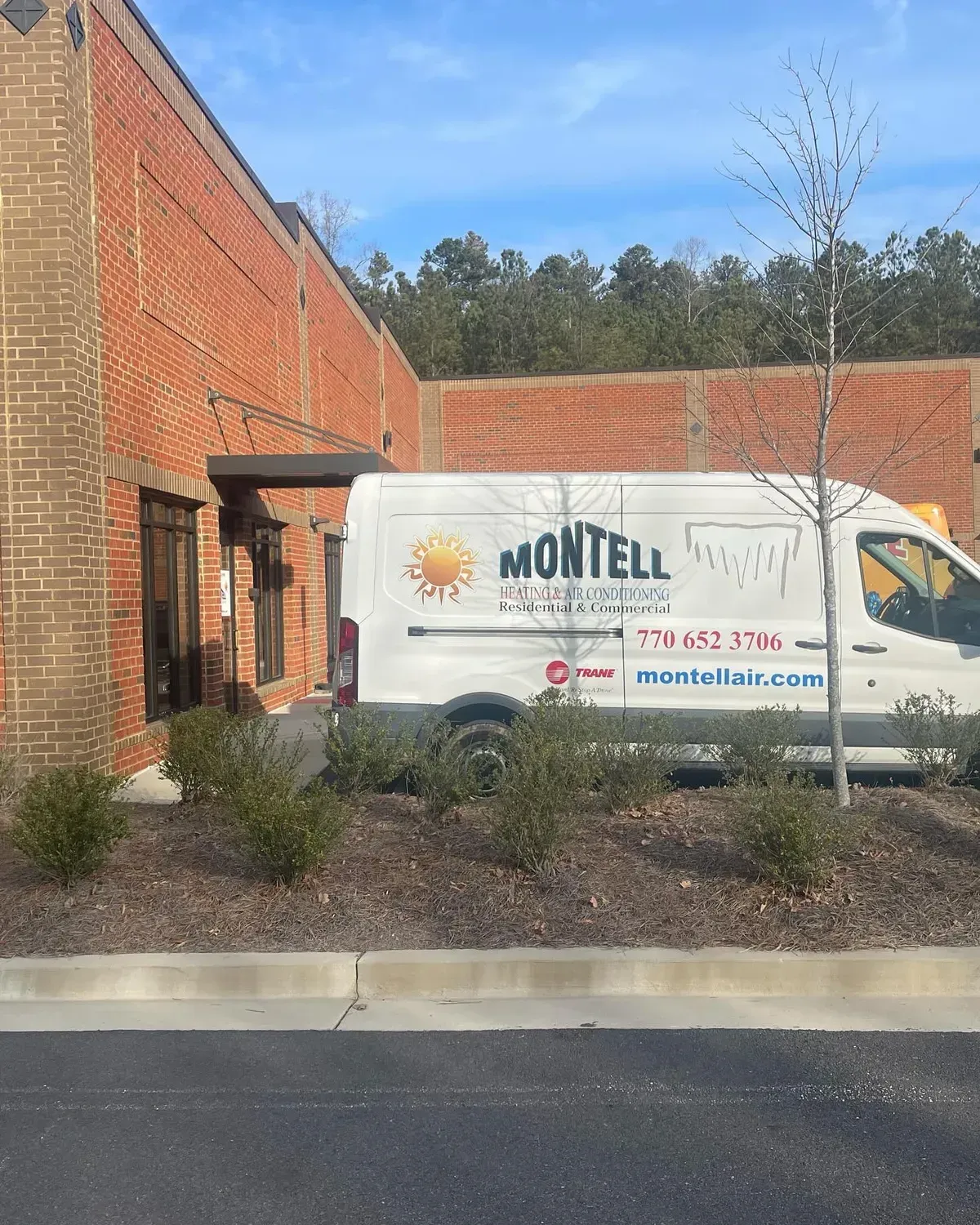 A white van is parked in front of a brick building.