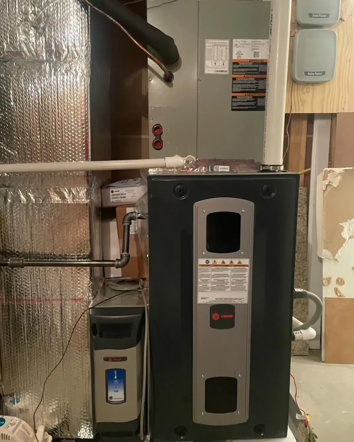 An air conditioner is sitting in a basement next to a wall.