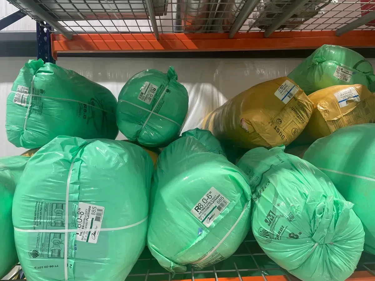A bunch of green bags are stacked on top of each other on a shelf.