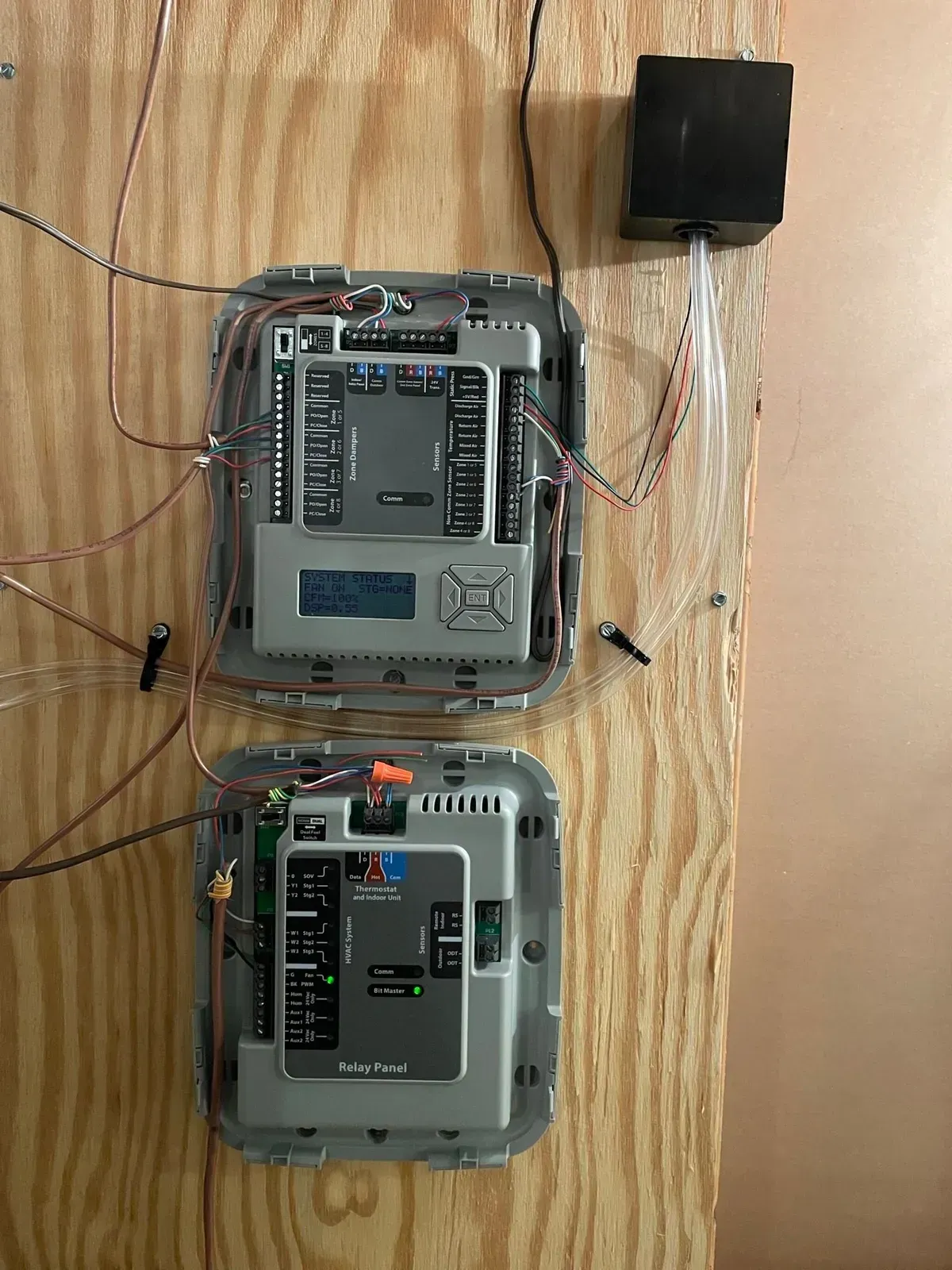 Two thermostats are sitting on top of a wooden table.