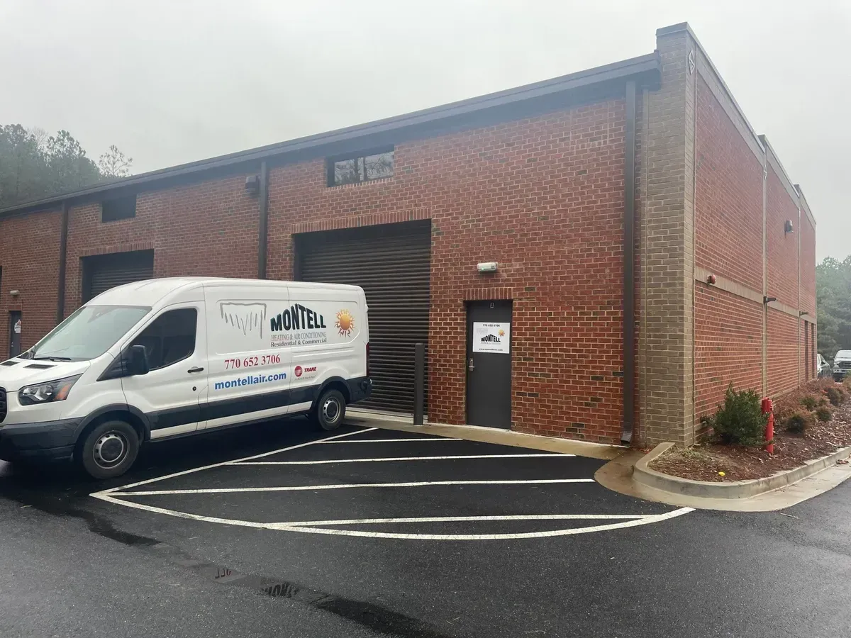 A white van is parked in front of a brick building.