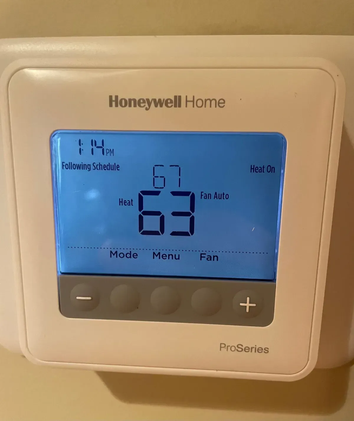 A honeywell home thermostat shows the temperature is 67 degrees