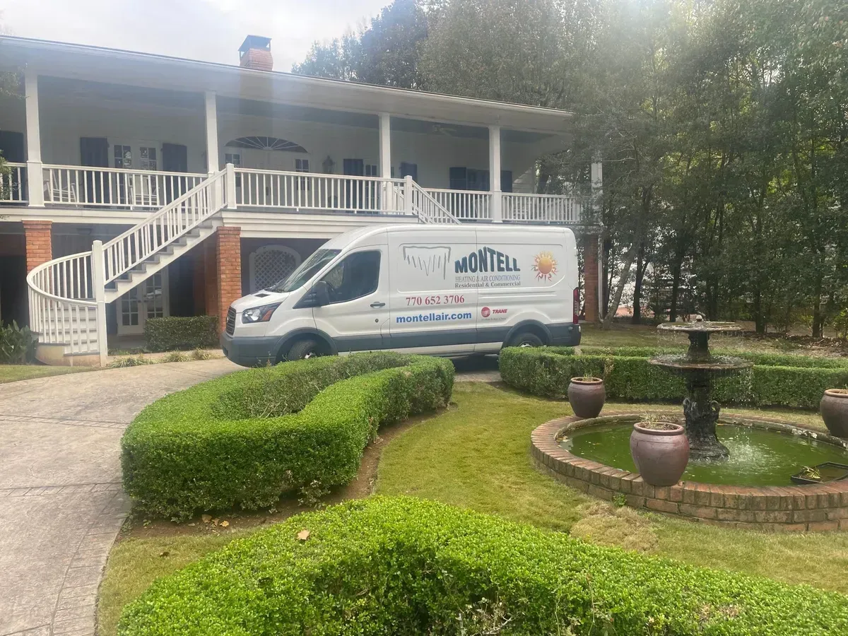 A white van is parked in front of a large white house.