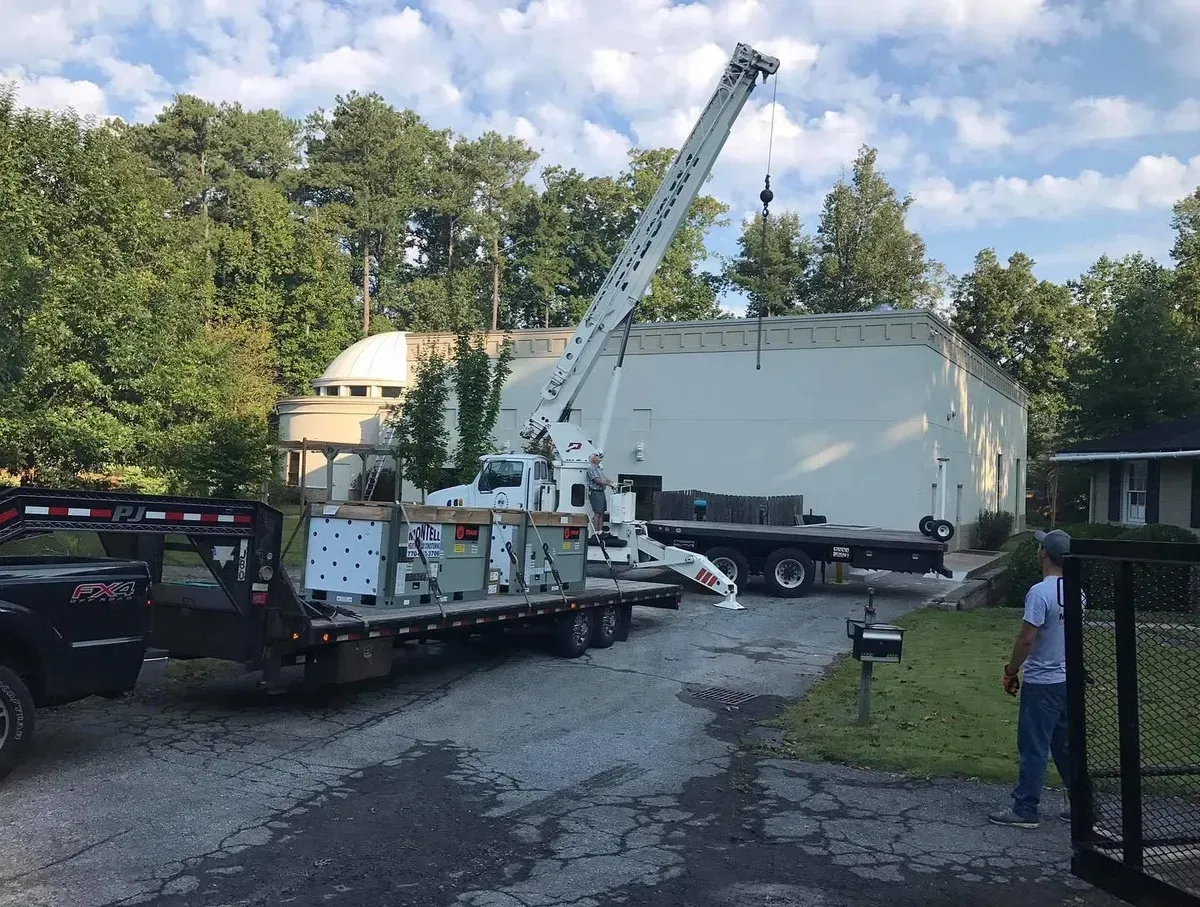 A truck with a crane on top of it is parked in front of a building.