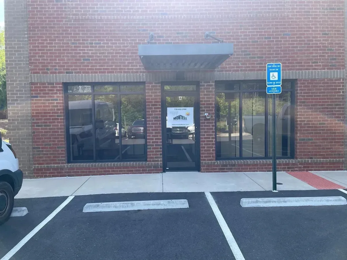 A white van is parked in front of a brick building.