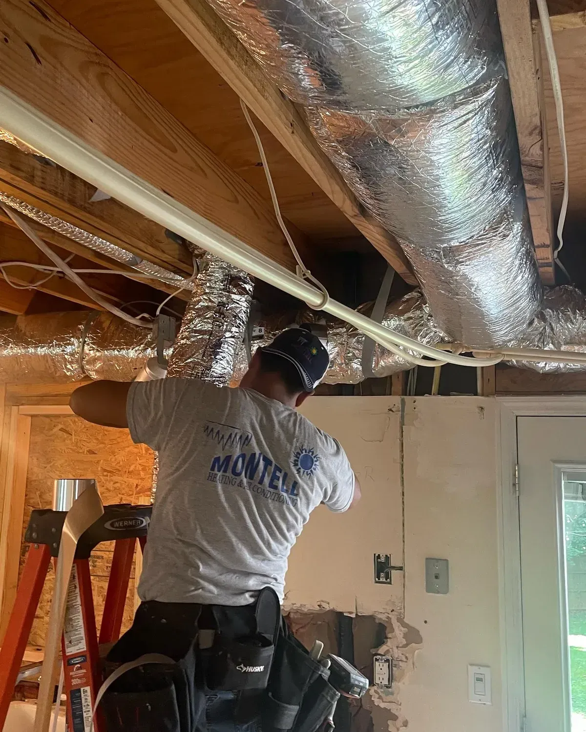 A man is standing on a ladder working on a ceiling.