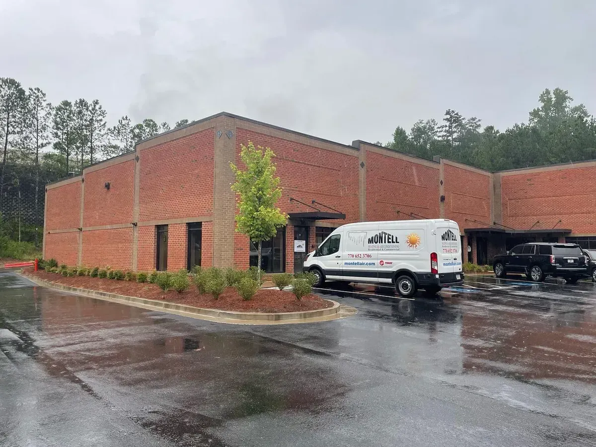 A white van is parked in front of a brick building on a rainy day.