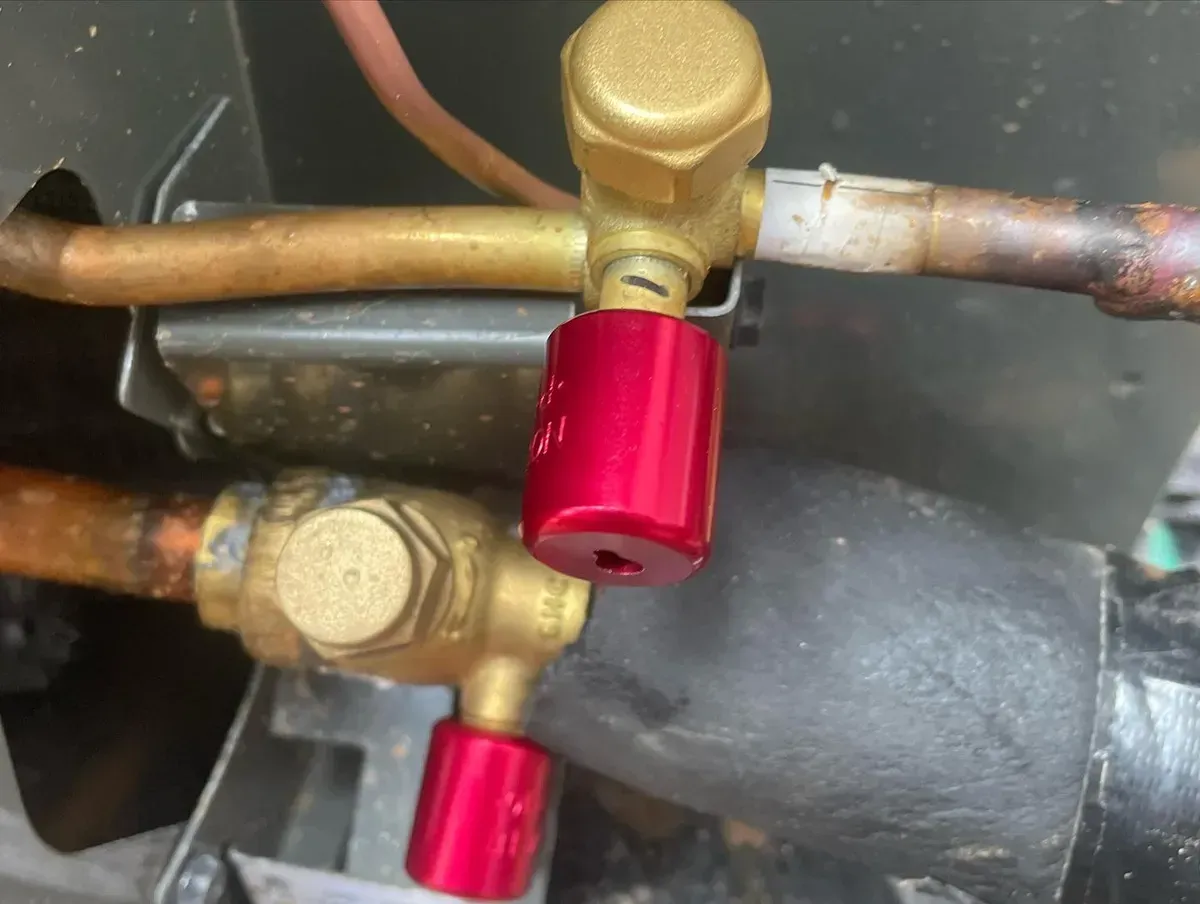 A close up of a red valve on a copper pipe.