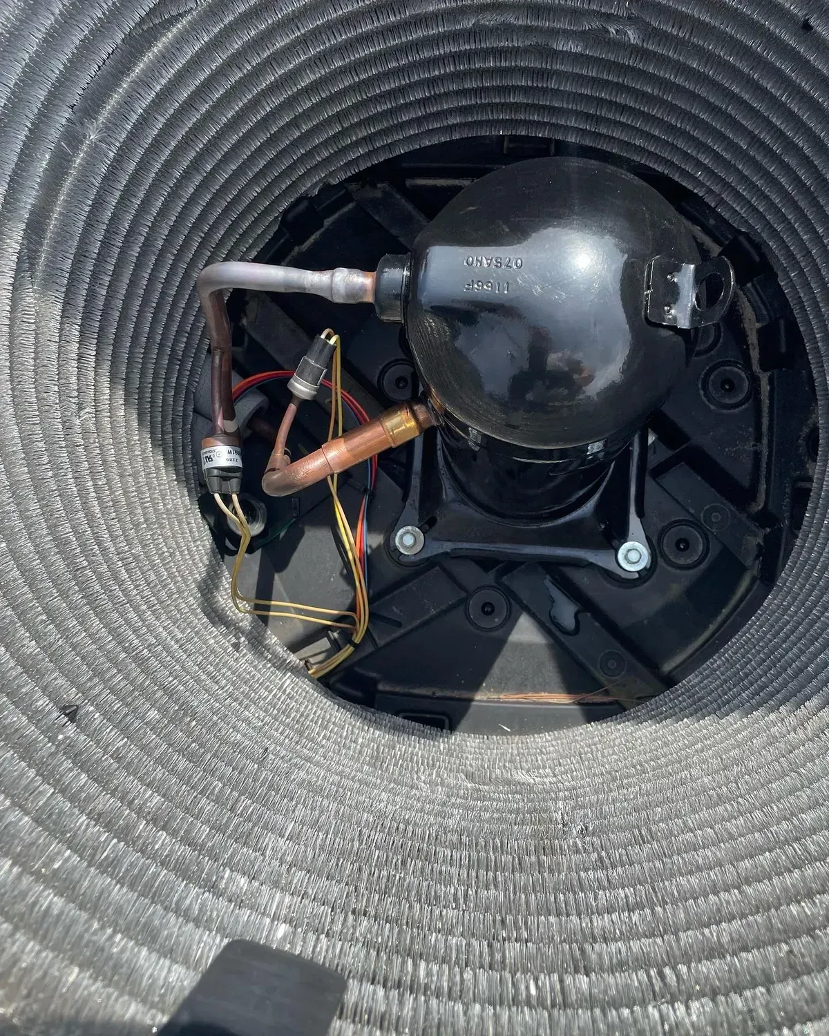 A close up of a compressor inside of an air conditioner.