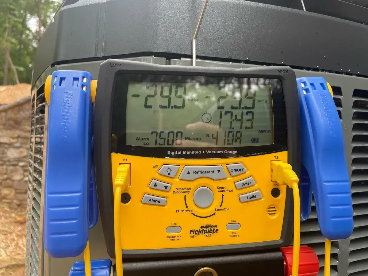 A yellow and black device is sitting on top of an air conditioner.