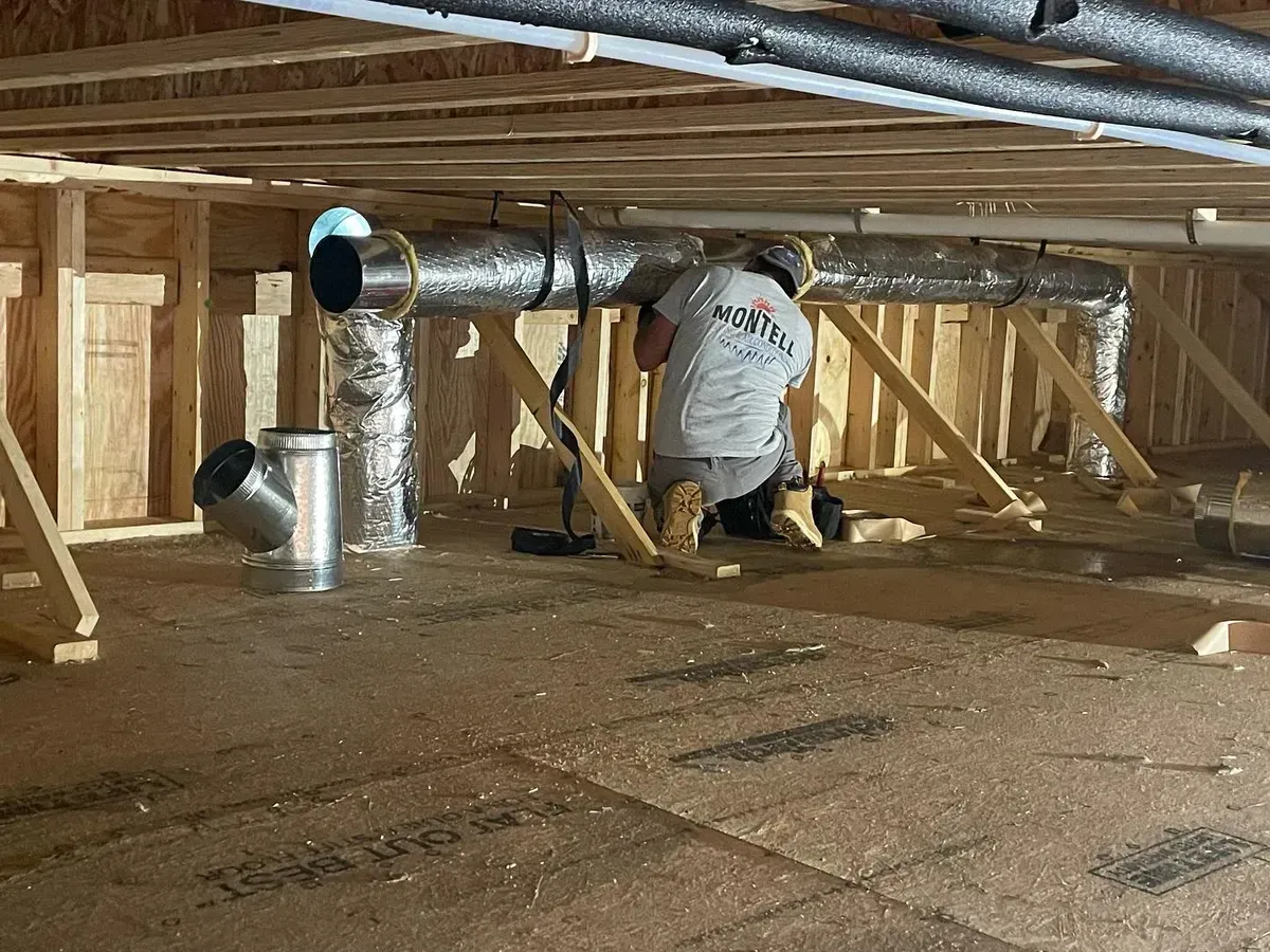 A man is kneeling down in a room under a house.