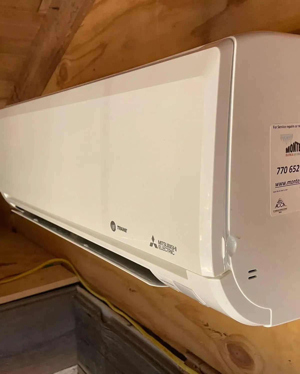 A white air conditioner is hanging from the ceiling in a room.