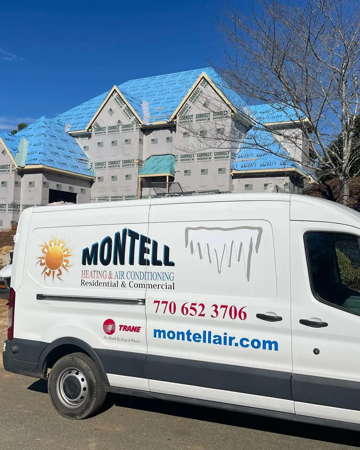 A white van is parked in front of a building under construction.