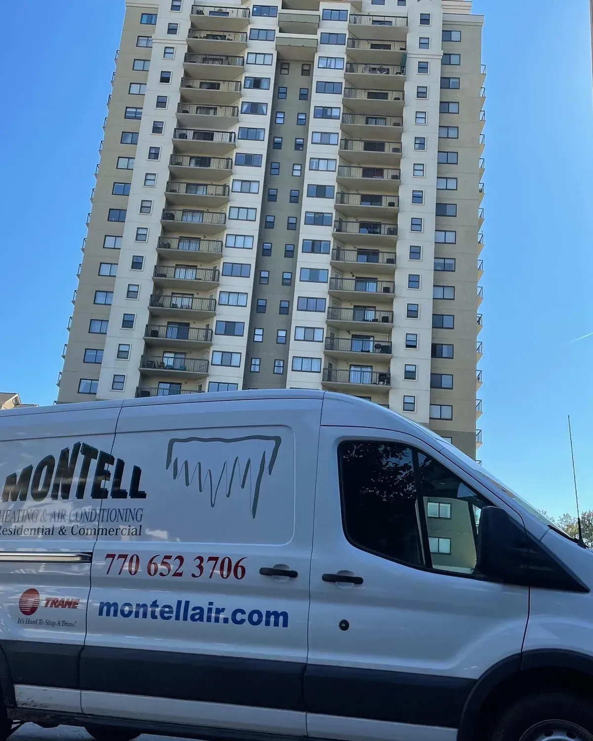 A montell van is parked in front of a tall building
