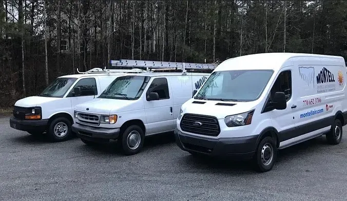 Three white vans are parked next to each other in a parking lot.