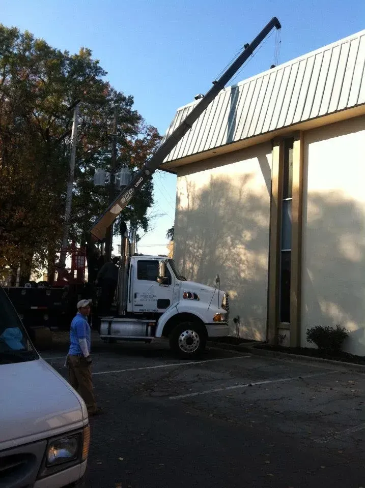 A truck with a crane attached to it is parked in front of a building