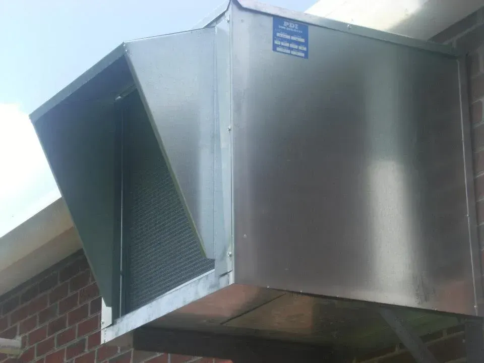 A large stainless steel box is attached to the side of a brick building.