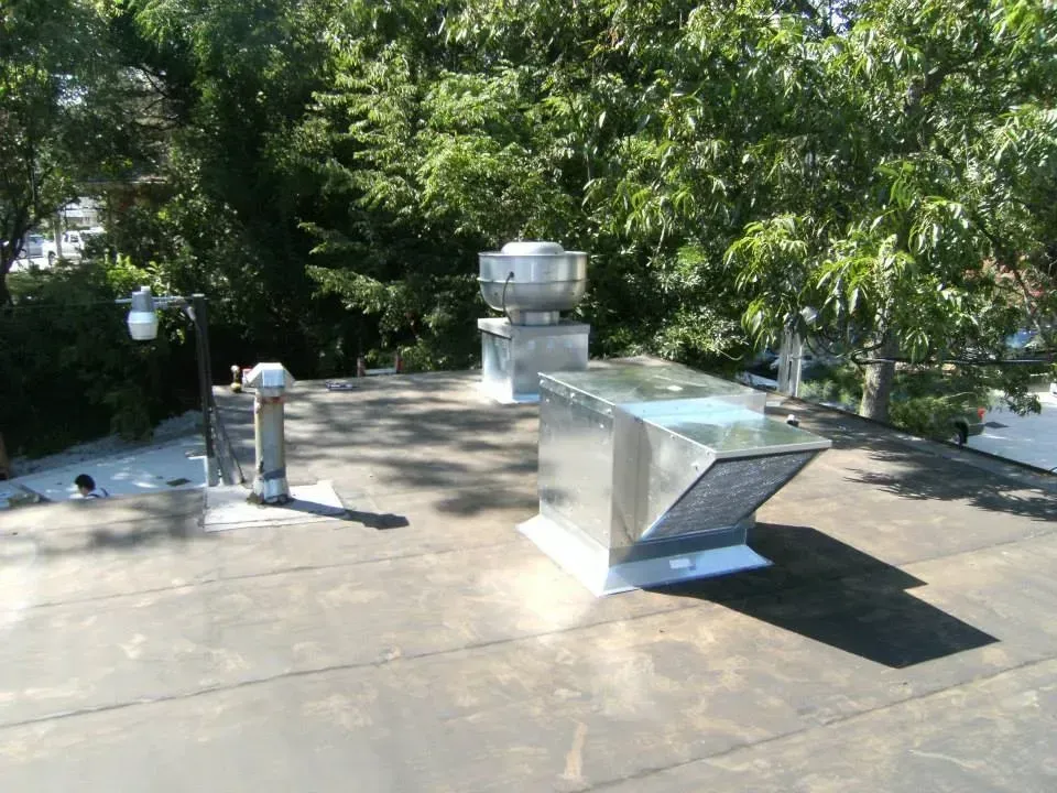 A roof with a chimney on it and trees in the background