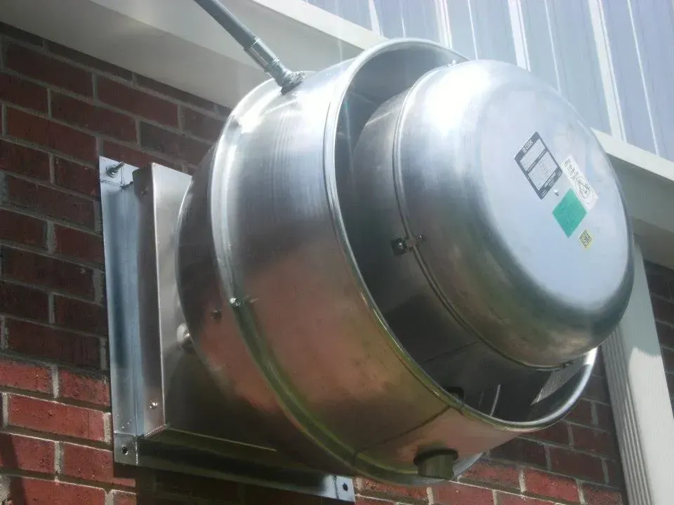 A large metal object is attached to a brick wall