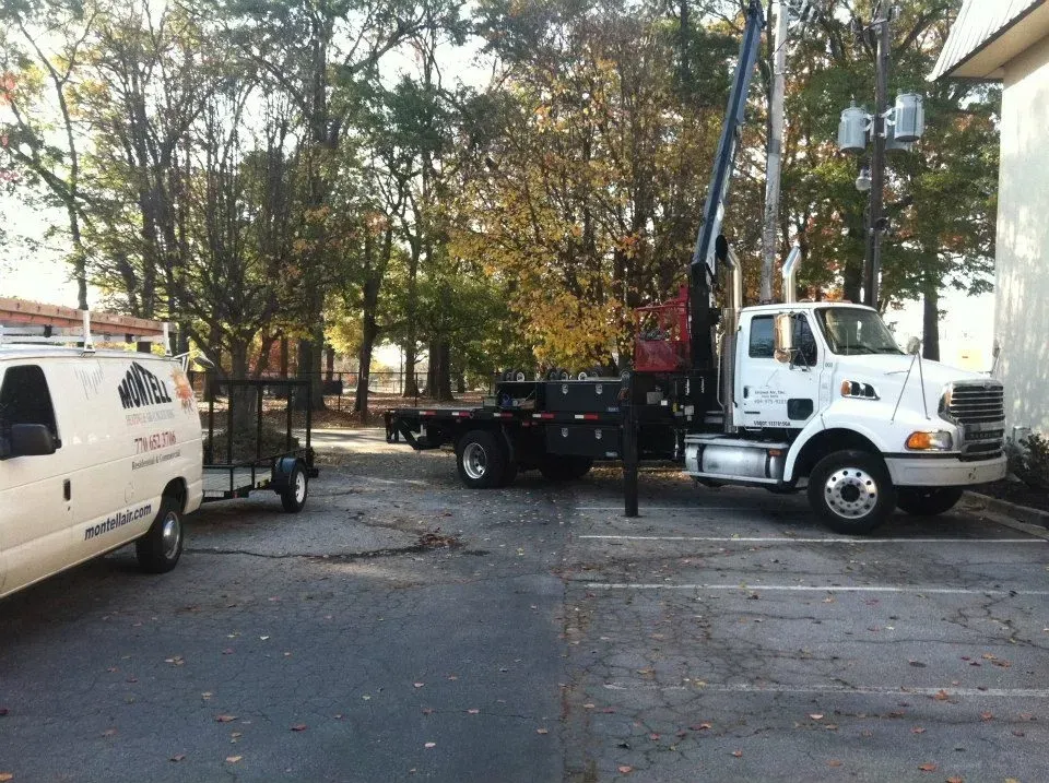 A truck with a crane attached to it is parked next to a white van